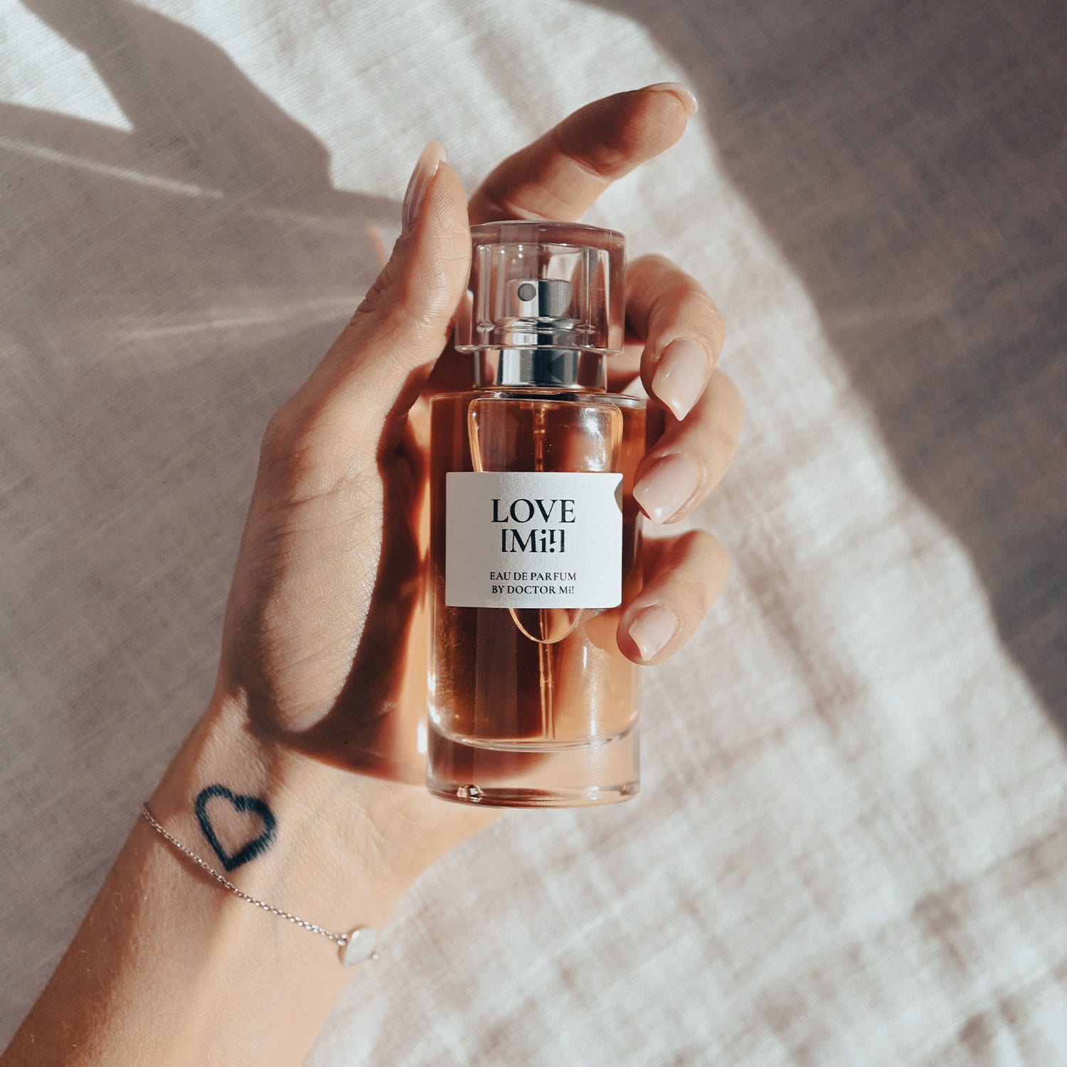 DOCTOR MI! LOVE MI! EAU DE PARFUM Duft mit verführerischen Sinnlichkeit in beiger Textur in Glasgefäß in Hand haltend 